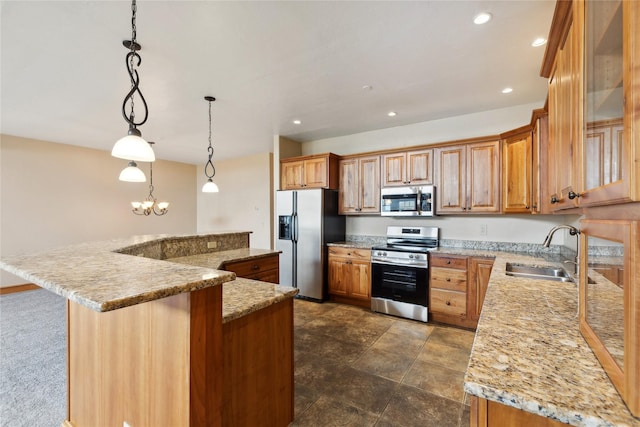 kitchen with brown cabinetry, stainless steel appliances, a sink, and decorative light fixtures