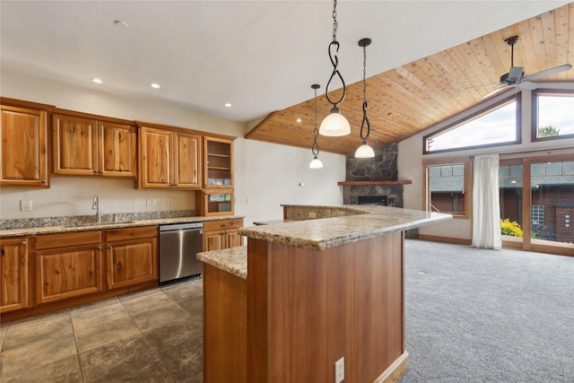 kitchen with a stone fireplace, a sink, stainless steel dishwasher, brown cabinets, and pendant lighting