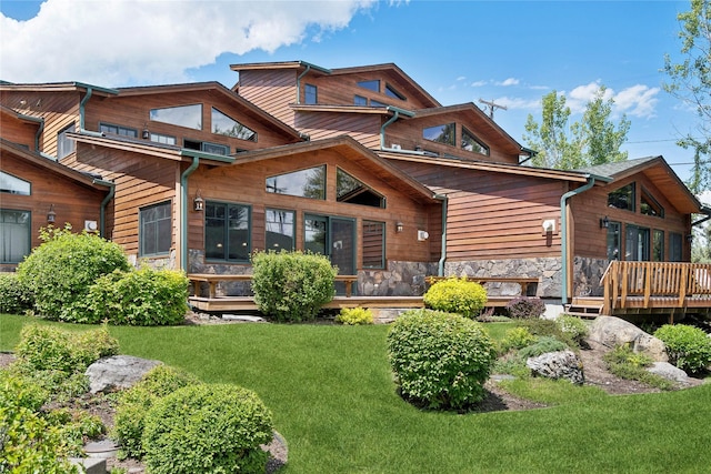 back of property with stone siding, a yard, and a wooden deck