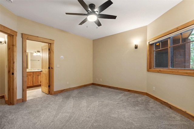 unfurnished bedroom featuring light carpet, ceiling fan, connected bathroom, and baseboards