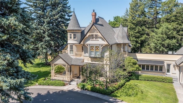 victorian-style house featuring covered porch and a front lawn