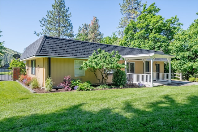 back of property with a porch, a yard, a shingled roof, and mansard roof