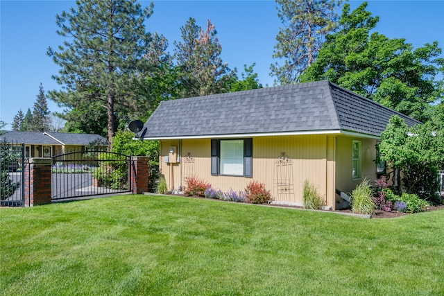 view of front of home featuring a shingled roof, mansard roof, fence, and a front lawn