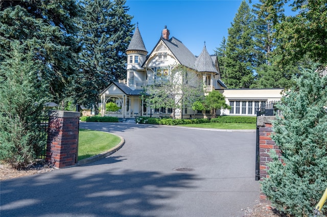 victorian house featuring aphalt driveway and a chimney