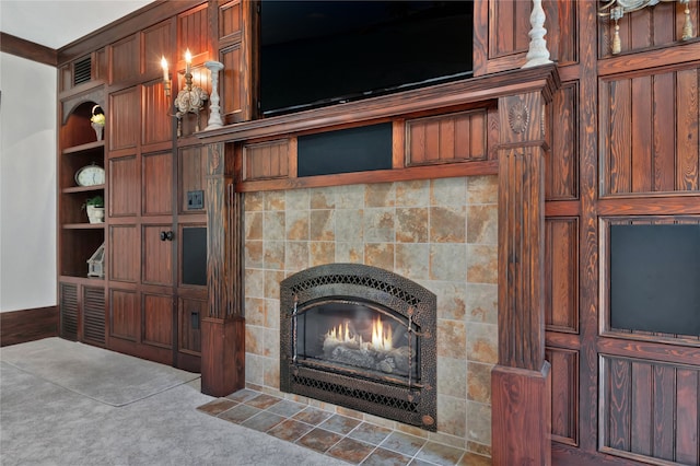 interior details featuring carpet flooring, a tiled fireplace, built in features, and ornamental molding