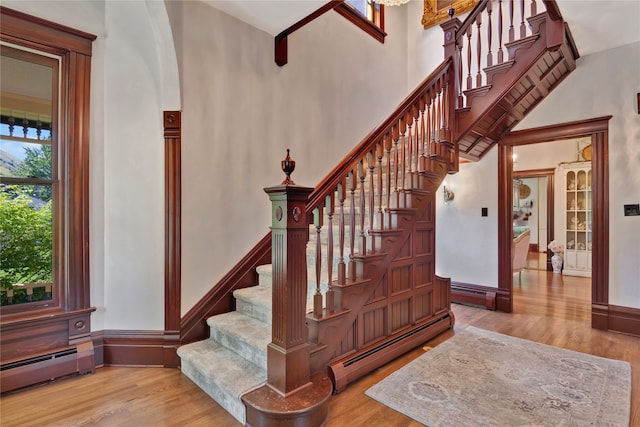 stairway with hardwood / wood-style flooring and a baseboard heating unit