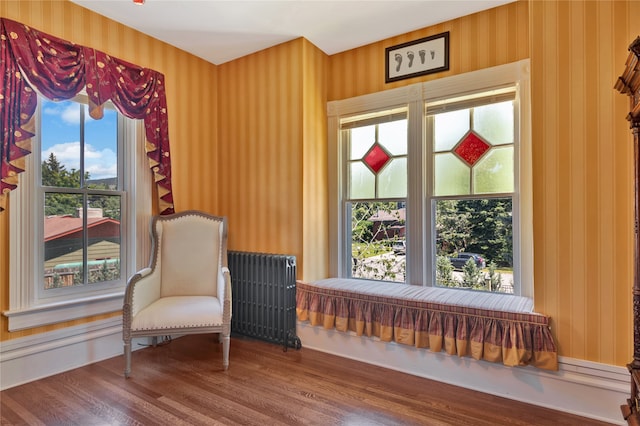 sitting room featuring radiator, wallpapered walls, and wood finished floors