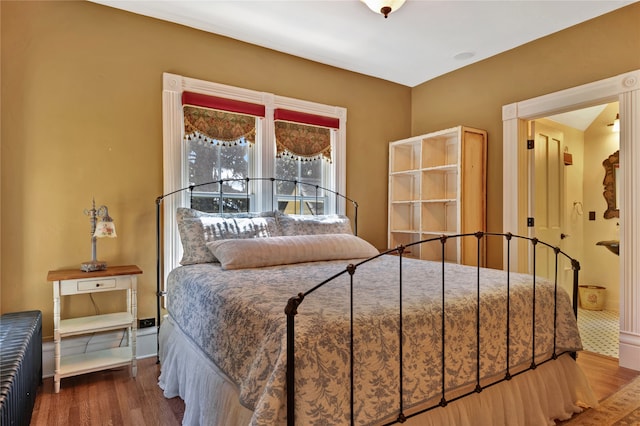 bedroom featuring baseboards, wood finished floors, and radiator