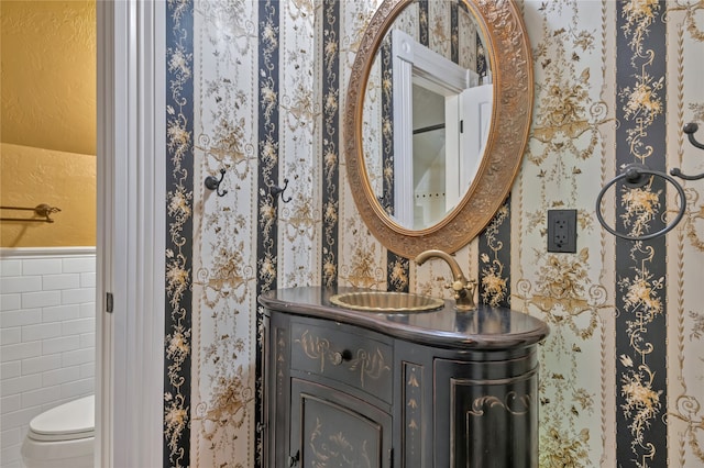 bathroom with vanity, toilet, and tile walls