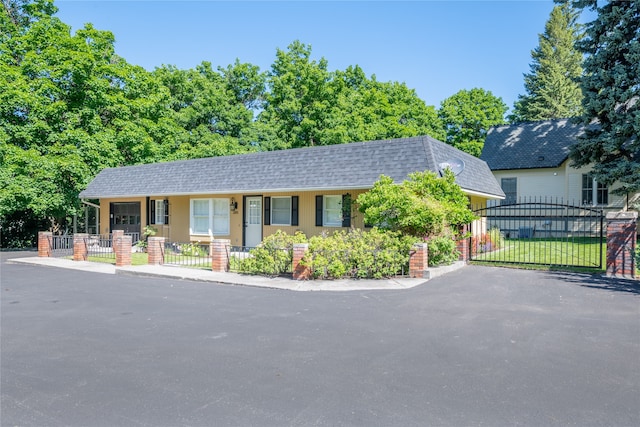 single story home with a shingled roof, a gate, a fenced front yard, and mansard roof