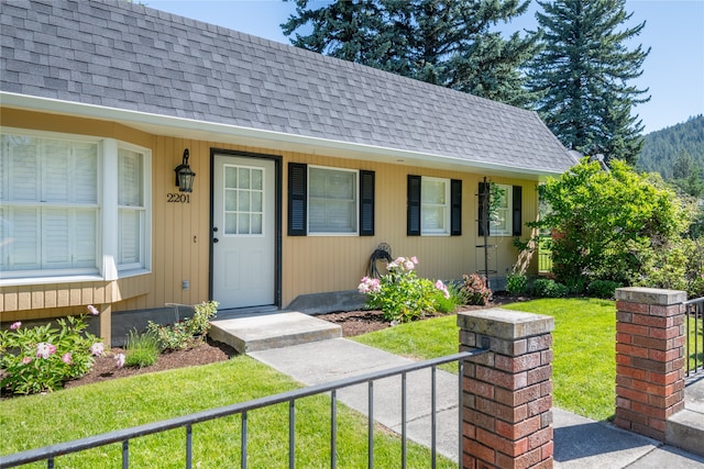 exterior space featuring a front yard, fence, and roof with shingles