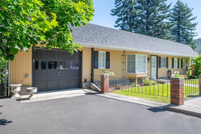 view of front of house with a garage, driveway, a shingled roof, and a fenced front yard