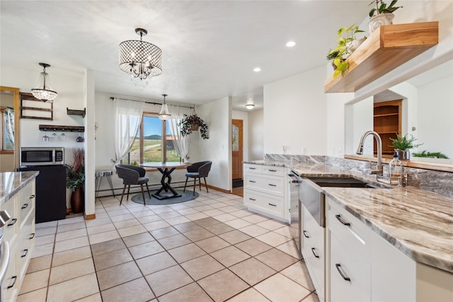 kitchen with pendant lighting, light stone countertops, light tile patterned floors, white cabinetry, and stainless steel appliances