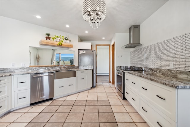 kitchen featuring appliances with stainless steel finishes, wall chimney exhaust hood, sink, a notable chandelier, and white cabinets