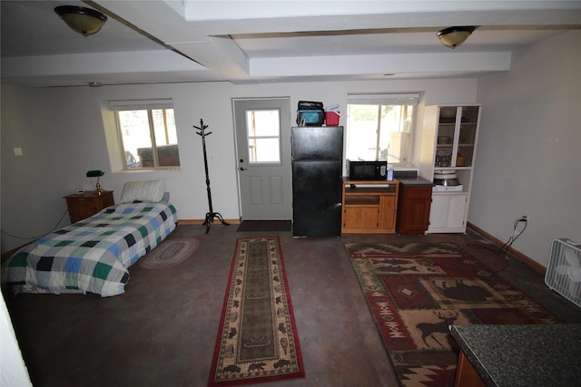 bedroom featuring beam ceiling, multiple windows, freestanding refrigerator, and baseboards