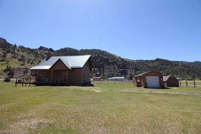 view of yard with driveway, a detached garage, fence, and an outdoor structure