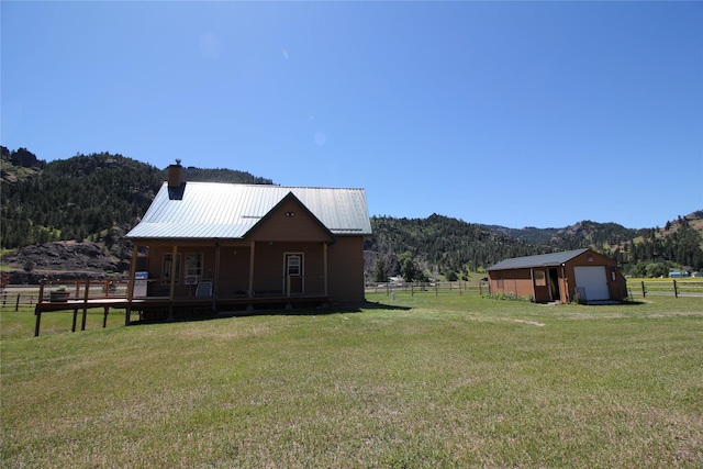 view of yard with fence, a mountain view, a wooded view, a garage, and an outdoor structure