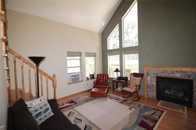 living room featuring a high end fireplace, wood finished floors, high vaulted ceiling, cooling unit, and stairs