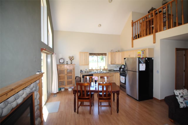 dining room featuring high vaulted ceiling, a fireplace, and light wood-style flooring