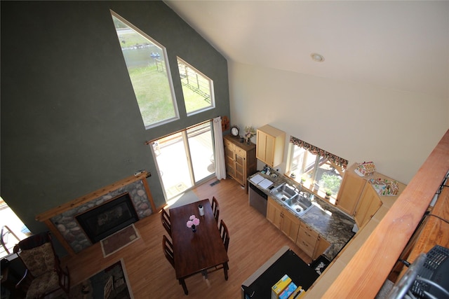 living area with high vaulted ceiling, light wood-type flooring, a tile fireplace, and a wealth of natural light