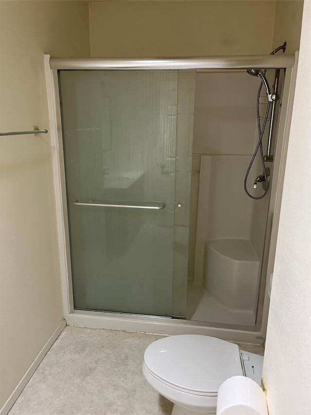 bathroom with a shower with door and toilet