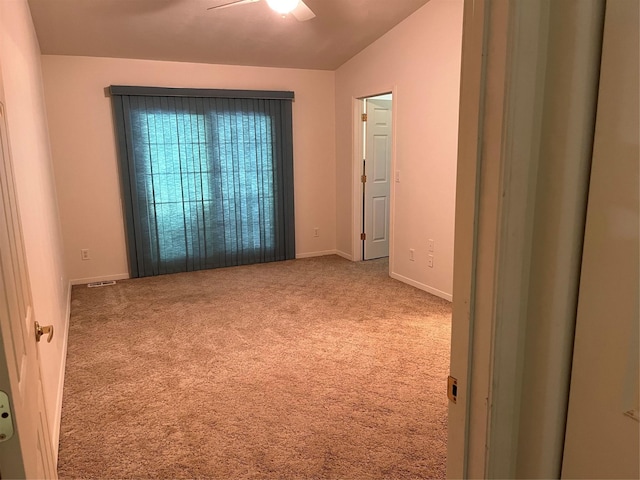 spare room featuring carpet floors, visible vents, baseboards, and ceiling fan