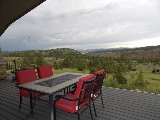 wooden terrace featuring a mountain view and outdoor dining space
