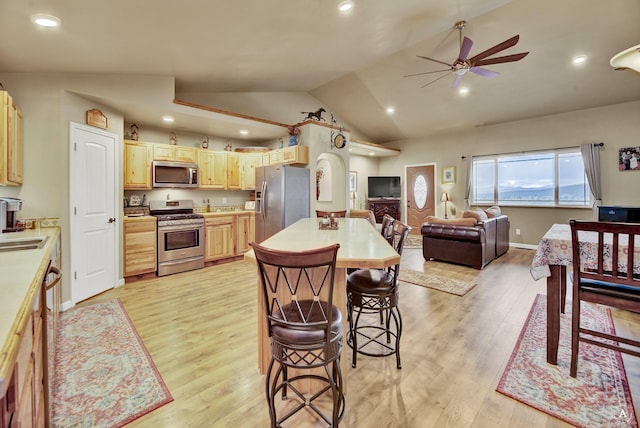 kitchen featuring ceiling fan, light countertops, stainless steel appliances, open floor plan, and lofted ceiling