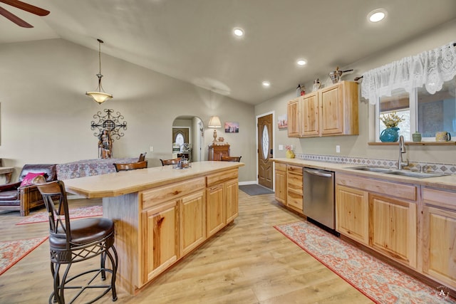 kitchen with stainless steel dishwasher, light brown cabinetry, arched walkways, a sink, and vaulted ceiling