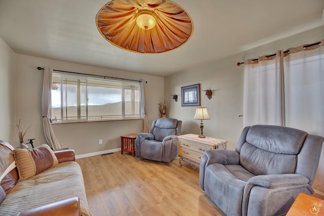 living room featuring baseboards, light wood-style flooring, and visible vents