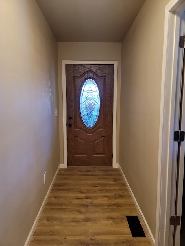 entryway with baseboards, visible vents, and wood finished floors
