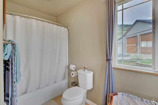 bathroom featuring baseboards, shower / bath combo with shower curtain, and toilet