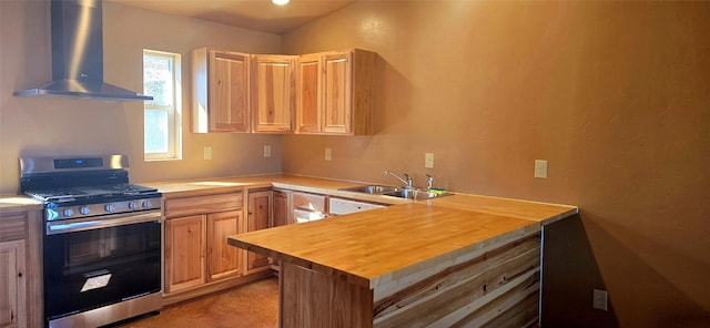 kitchen featuring wall chimney range hood, a sink, stainless steel gas range oven, butcher block countertops, and a peninsula
