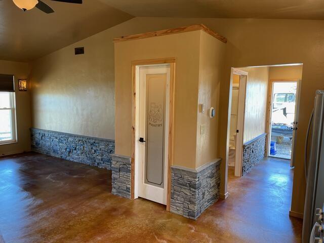 interior space with plenty of natural light, a ceiling fan, vaulted ceiling, and visible vents