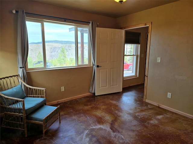 sitting room featuring baseboards, a mountain view, finished concrete floors, and a wealth of natural light
