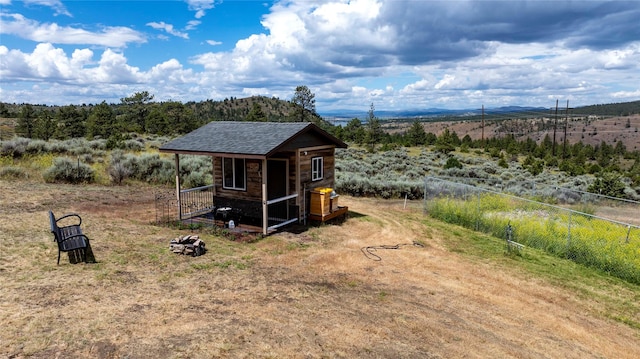 view of outdoor structure featuring a rural view, fence, and an outdoor structure
