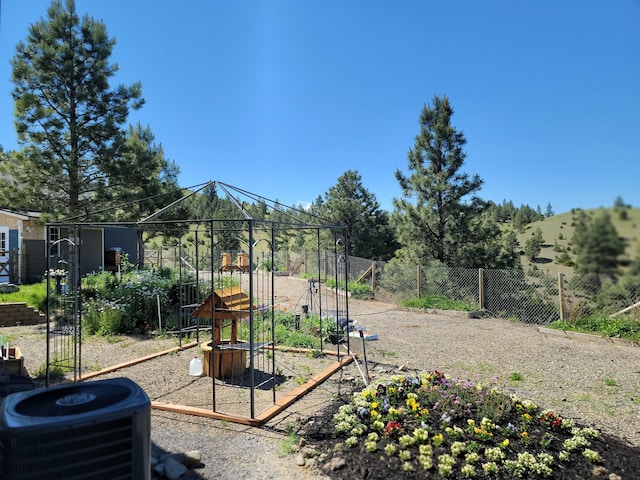 view of play area with a garden, fence, and cooling unit