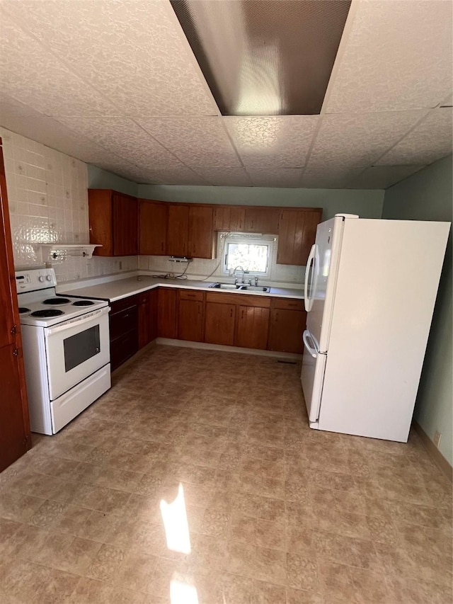 kitchen featuring a drop ceiling, white appliances, and sink