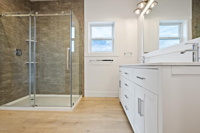 bathroom with hardwood / wood-style floors, vanity, and a shower with shower door