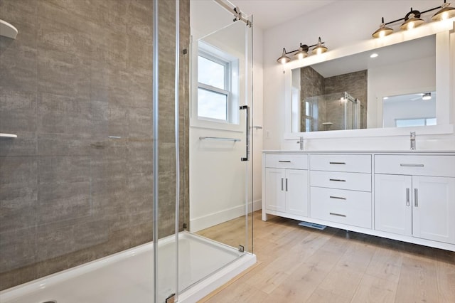 bathroom featuring hardwood / wood-style floors, vanity, and a shower with shower door