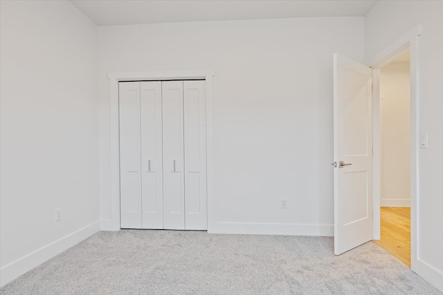 unfurnished bedroom featuring a closet and light colored carpet