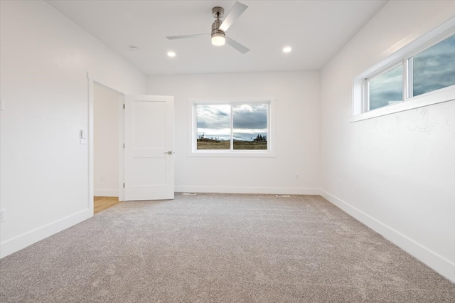 empty room featuring ceiling fan and light colored carpet