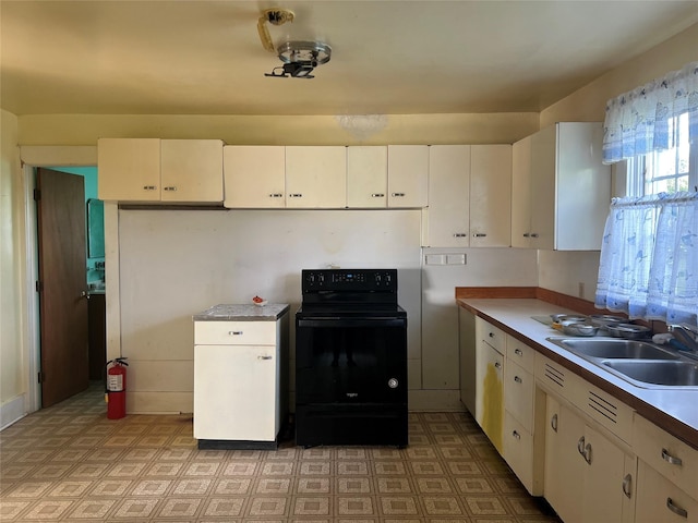 kitchen with white cabinets, black / electric stove, and sink