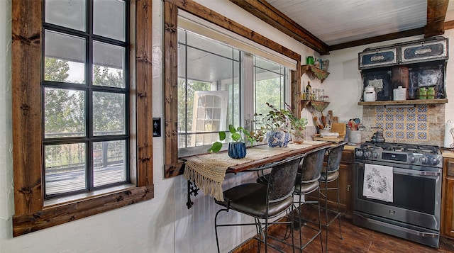 kitchen featuring stainless steel gas stove, backsplash, beam ceiling, and dark wood-type flooring