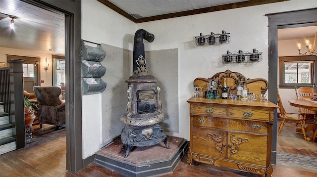 room details featuring a notable chandelier, crown molding, wood-type flooring, and a wood stove