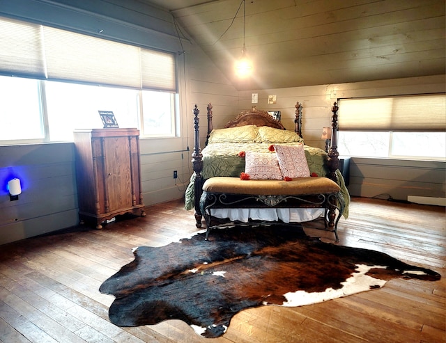 bedroom featuring lofted ceiling, hardwood / wood-style floors, and wooden walls