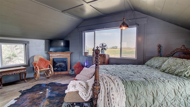 bedroom with wood-type flooring, wood walls, and vaulted ceiling