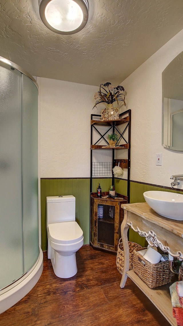 bathroom with toilet, hardwood / wood-style floors, a textured ceiling, and a shower with shower door