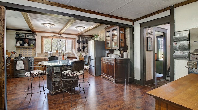 dining space with dark hardwood / wood-style floors, a textured ceiling, and beam ceiling