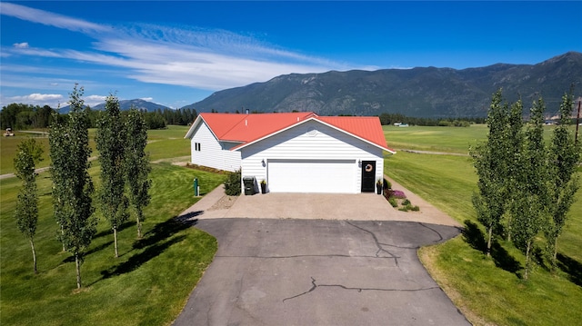 view of front facade with a garage, a mountain view, and a front yard